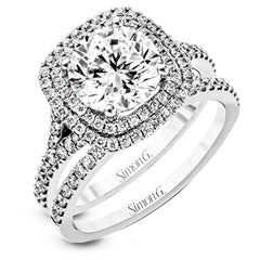 This remarkable white gold engagement ring and wedding band set features a contemporary setting with an eye-catching halo highlighted by .67 ctw of round cut white diamonds.