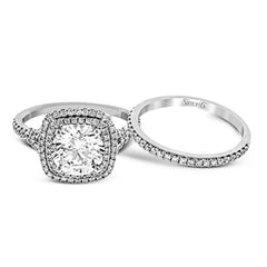 This remarkable white gold engagement ring and wedding band set features a contemporary setting with an eye-catching halo highlighted by .67 ctw of round cut white diamonds.