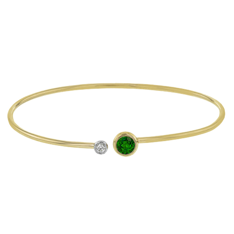 This understated yellow gold bangle features a subtle .08 ctw white diamond accent opposite a stunning .65 ctw emerald. Perfect for stacking.