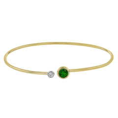 This understated yellow gold bangle features a subtle .08 ctw white diamond accent opposite a stunning .65 ctw emerald. Perfect for stacking.